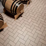 Three wooden barrels on a herringbone-patterned tile floor with industrial tiles Lahore, creating a rustic and orderly ambiance with warm lighting.